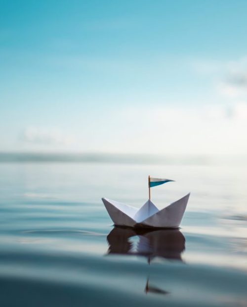 Small,Paper,Boat,Is,Floating,On,Calm,Water